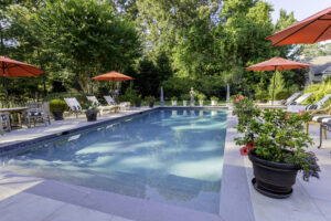 Classic concrete pool with full steps and porcelain paver patio