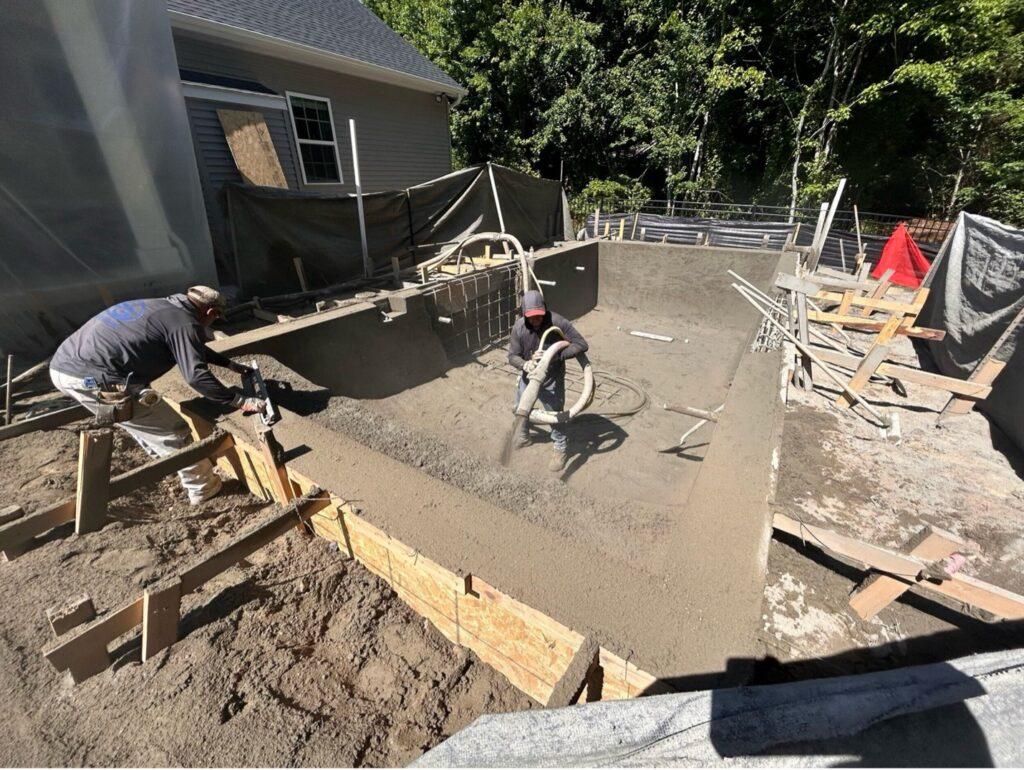 construction workers spraying Gunite forming a customized pool