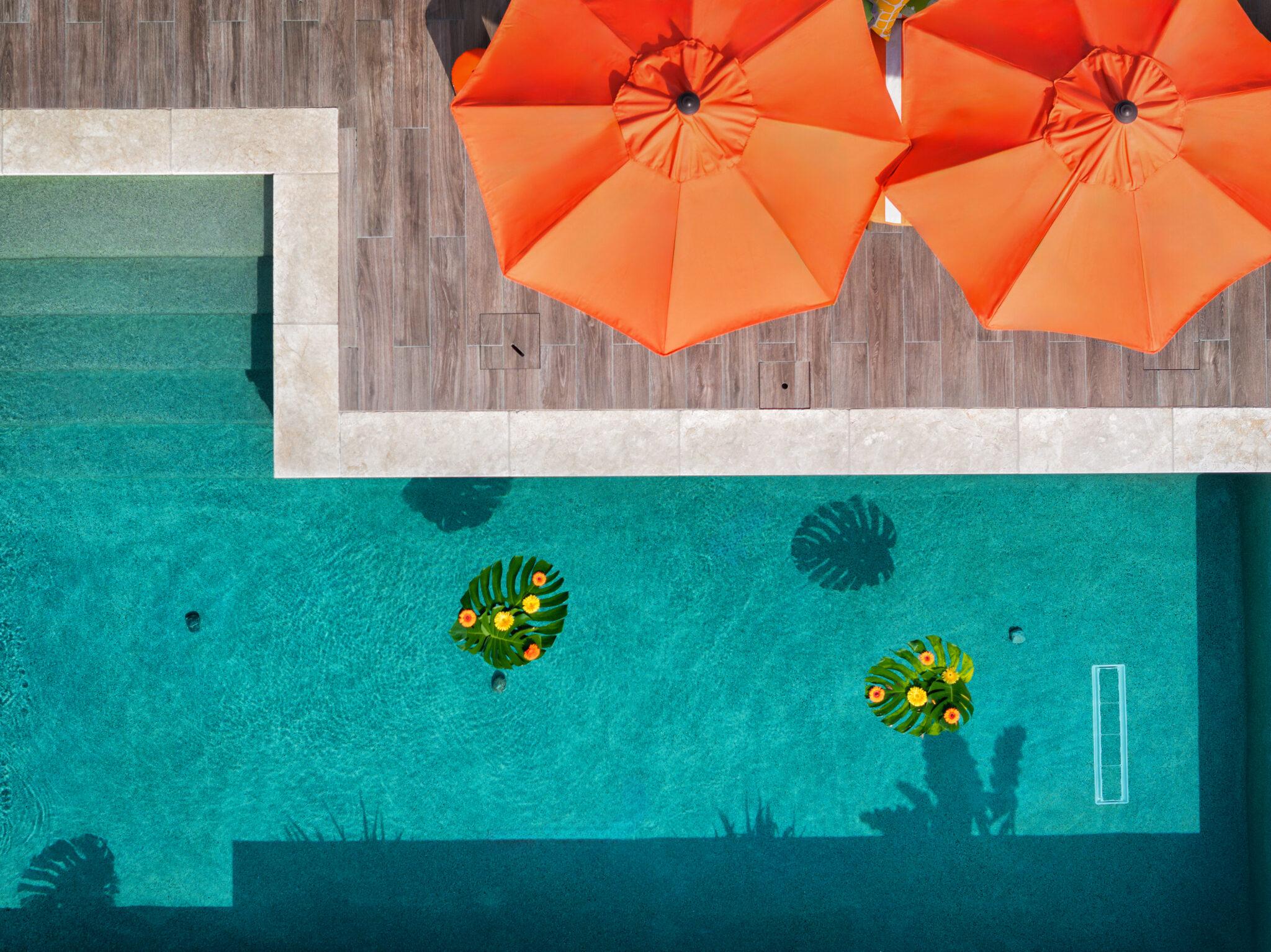 An aerial view of a custom Gunite pool with umbrellas and a tennis ball