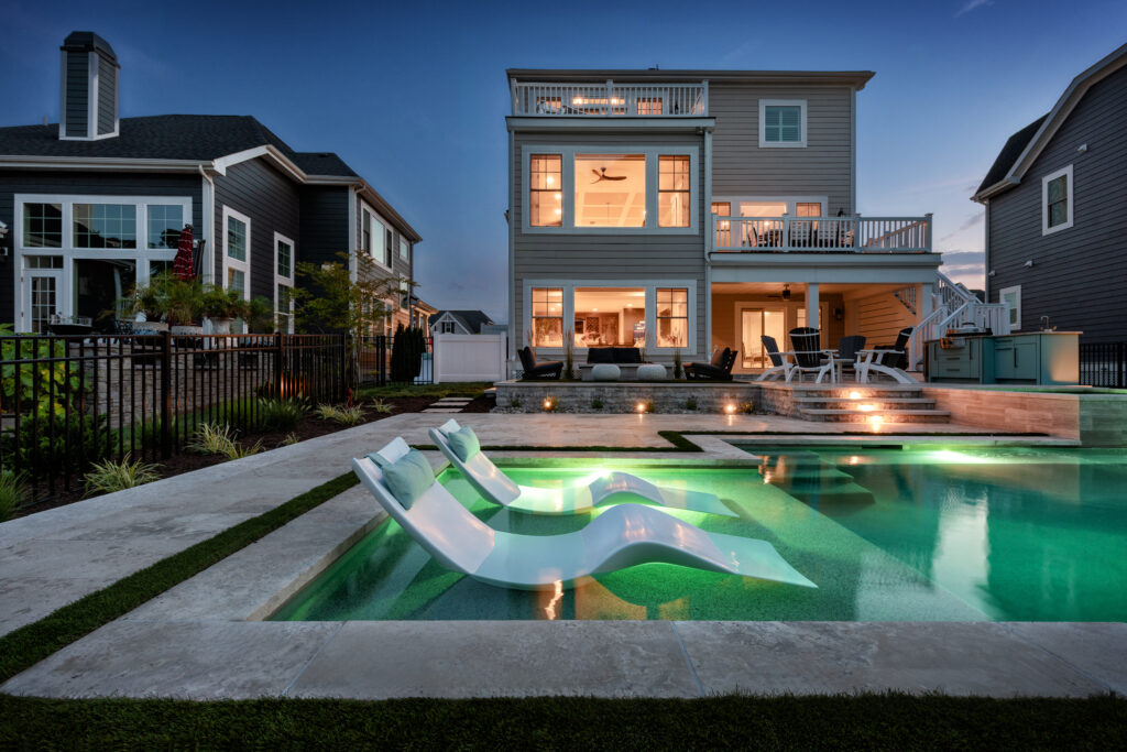 Custom gunite pool with lighting, ledge loungers and shown in the dark with the lights on