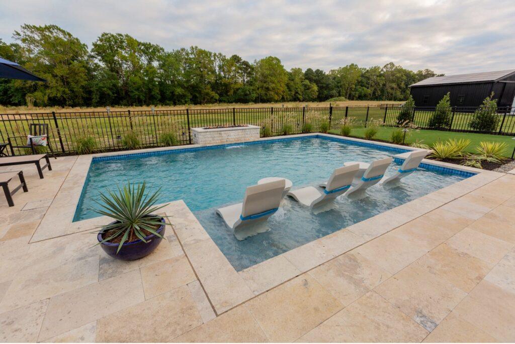 An outdoor custom pool with ledge loungers, firepit, pavers and beautiful pool tile all chosen at the material selections meeting 