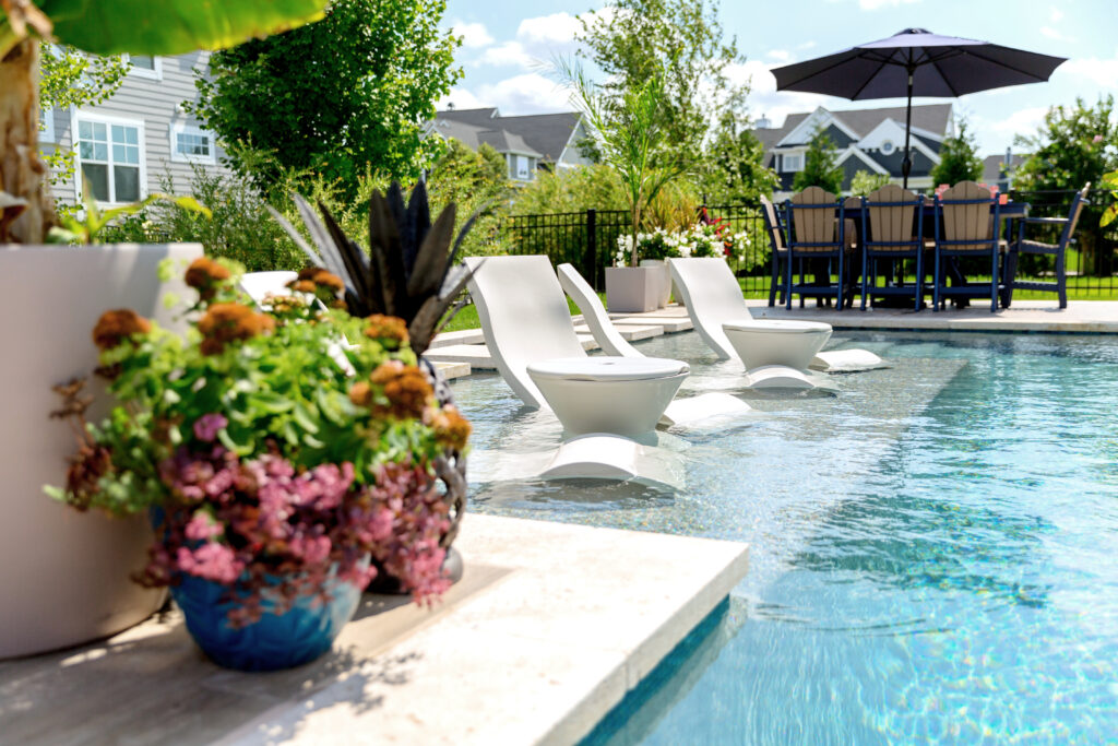 photo of ledge in pool with ledge lounger furniture along with beautiful landscaping